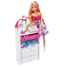 Barbie mit zwei Babys auf einem Wickeltisch, hält ein Mobile über ihnen dazu Zubehör fürs Kinderzimmer.