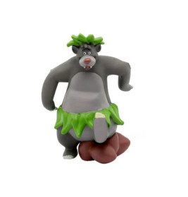 Cartoon-Bär mit grünem Blätterrock und Kopfschmuck, lächelnd und tanzend mit erhobenem Bein.