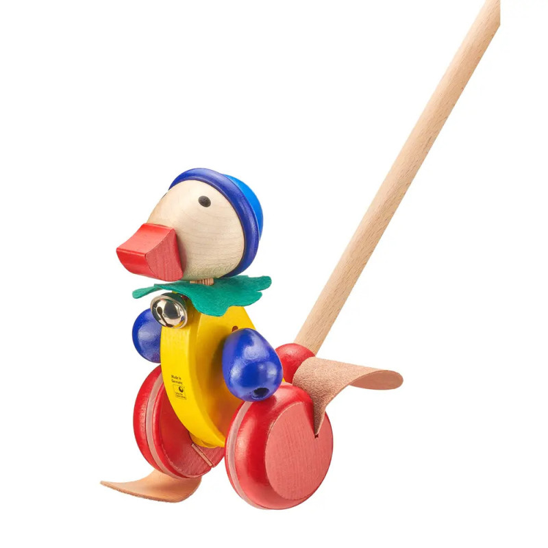 Holz-Enten-Schiebespielzeug mit roten Rädern, gelbem Körper, blauem Hut und beweglichen Füßen an Holzstab. Holz-Enten-Schiebespielzeug mit roten Rädern, gelbem Körper, blauem Hut und beweglichen Füßen an Holzstab.
