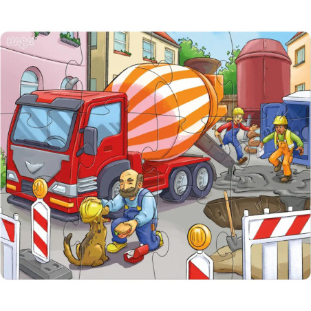 Ein Betonmischer auf einer Baustelle, Arbeiter und ein Hund bei Absperrungen und einer Baugrube.