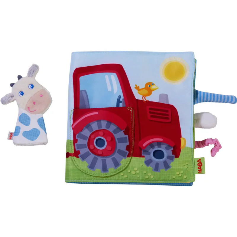 Stoffbuch mit rotem Traktor, gelbem Vogel und einer Plüschkuh daneben auf weißem Hintergrund.