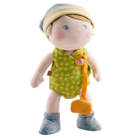 Plüschpuppe mit grünem Outfit, blauer Mütze, grauen Schühchen und einem am Kleid befestigten Schnuller.