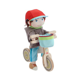 Stoffpuppe mit rotem Helm fährt auf einem Holzfahrrad mit blauem Korb vor weißem Hintergrund.