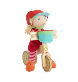 Plüschpuppe mit rotem Helm fährt auf Holz-Dreirad mit blauem Korb, vor weißem Hintergrund.