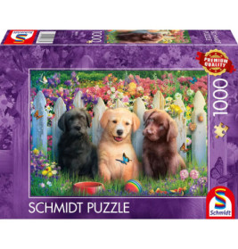 Puzzlebox mit drei Welpen im Gras vor weißem Zaun, dahinter bunte Blumen und Schmetterlinge.