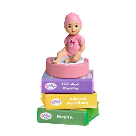 Eine kleine Puppe in Pink sitzt auf bunten, gestapelten Boxen mit deutscher Beschriftung an den Seiten.