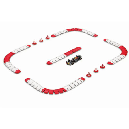 Ein Spielzeugauto fährt auf einer Strecke mit rot-weißen Barrieren und orangenen Kegeln vor weißem Hintergrund.