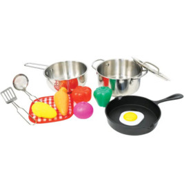 Spielküche mit Töpfen, Utensilien, Spielzeuggemüse und Spiegelei in Pfanne auf weißem Hintergrund.