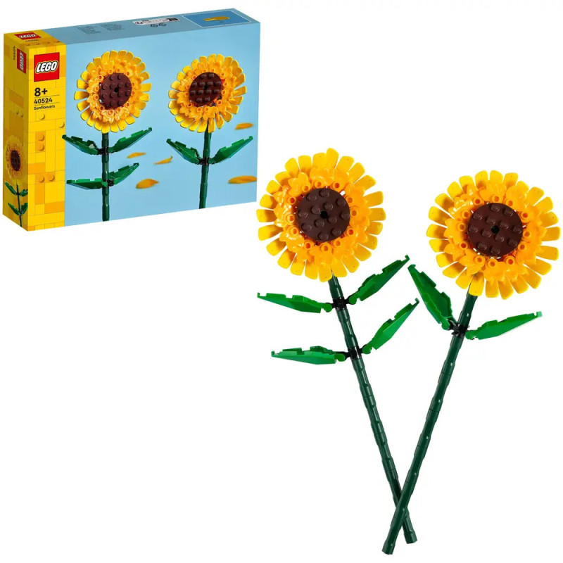 Zwei aus LEGO gebaute Sonnenblumen mit grünen Stielen vor ihrer blau-gelben Verpackung.