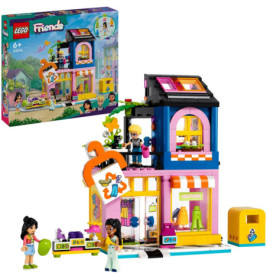 LEGO Friends Set mit buntem zweistöckigem Gebäude, drei Minifiguren, Zubehör und der Verpackung im Hintergrund.