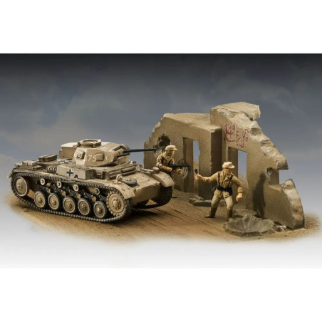 Modellpanzer und zwei Spielfiguren stehen neben einer beschädigten, bemalten Mauer in einer Wüstenszene. Modellpanzer und zwei Spielfiguren stehen neben einer beschädigten, bemalten Mauer in einer Wüstenszene.