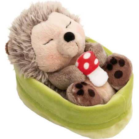 Ein Plüschigel liegt mit geschlossenen Augen friedlich im grünen Bett und hält einen rot-weißen Pilz.