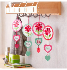 Vier bunte Hänge-Basteleien mit Herzen und Blumen, mit den Aufschriften Papa, Mama und Alles Liebe an Wandhaken.