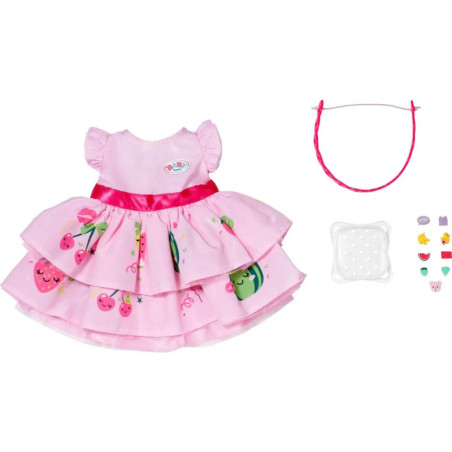 Rosa Puppenkleid mit Fruchtmotiven, rosa Haarband, transparente Schuhe und kleine bunte Accessoires.