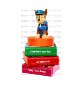 Eine Paw Patrol Chase-Figur steht auf einem Stapel bunter Bücher mit verspielten Titeln.
