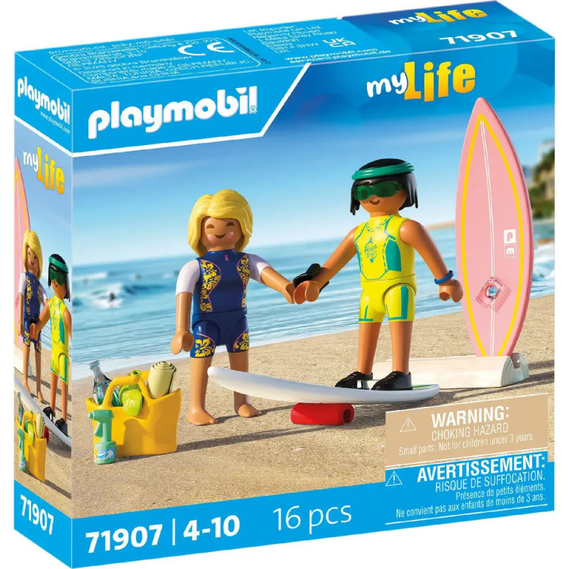 Zwei Playmobil-Figuren in Badekleidung stehen samt Surfbrett, Kamera und Zubehör auf Sand in einer Spielbox. Zwei Playmobil-Figuren in Badekleidung stehen samt Surfbrett, Kamera und Zubehör auf Sand in einer Spielbox.