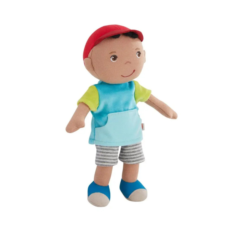 Plüschpuppe mit roter Mütze, blauem Shirt, gestreiften Shorts und blauen Schuhen vor weißem Hintergrund.