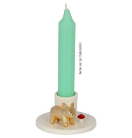 Grüne Kerze in weißem Halter, verziert mit kleinem goldenen Tier und rotem Punkt am Sockel.