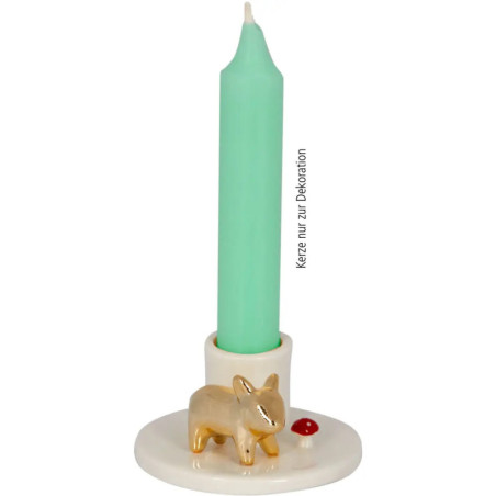 Grüne Kerze in weißem Halter, verziert mit kleinem goldenen Tier und rotem Punkt am Sockel.