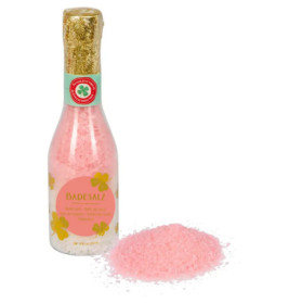 Eine Flasche rosa Badesalz mit der Aufschrift Badesalz, davor ausgeschüttetes Salz.