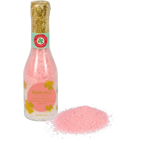Eine Flasche rosa Badesalz mit der Aufschrift Badesalz, davor ausgeschüttetes Salz.
