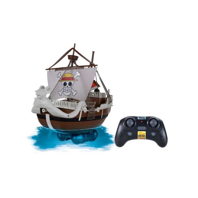 Ferngesteuertes Piratenschiff mit Totenkopfsegel steht neben schwarzer Fernbedienung auf blauem Untergrund.