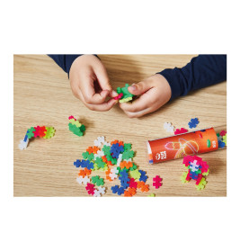 Kinderhände legen bunte Puzzle-Teile auf einen Holztisch, daneben steht ein roter Behälter.