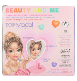Verpackung eines herzförmigen LED-Schminkspiegels mit Zeichnung eines Mädchens beim Schminken und Zubehör.