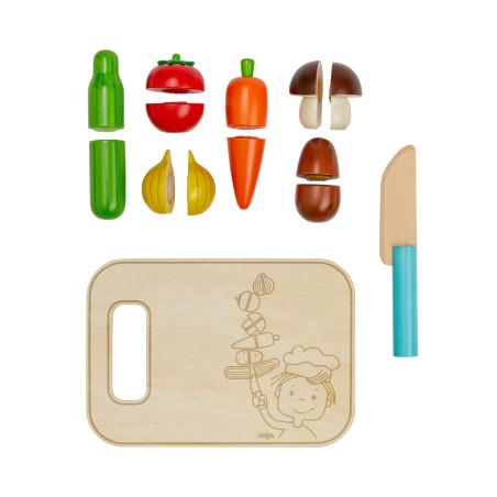 Holzspielzeug-Gemüse, Schneidebrett und Messer für Rollenspiele, ordentlich auf weißem Hintergrund angeordnet.