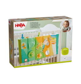 HABA Spielzeugbox fürs Babybett mit buntem Hänge-Panel, Verpackung zeigt lächelndes Baby.