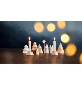 Holz- und Keramikbäume mit zwei brennenden Kerzen auf einem Tisch, unscharfe gelbe Lichter im Hintergrund.