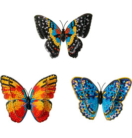 Drei bunte Schmetterlingsbasteleien aus Perlen liegen auf weißem Hintergrund.