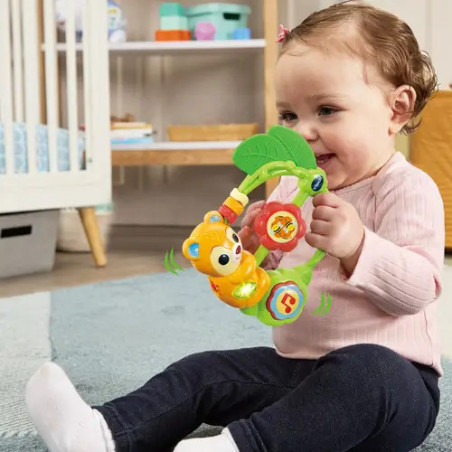Ein lächelndes Baby spielt auf einem blauen Teppich im Kinderzimmer mit buntem Spielzeug.