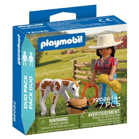 Playmobil-Set mit Frau im Hut, Kalb, Heuballen und weiteren Bauernhof-Zubehörteilen in ländlicher Umgebung.
