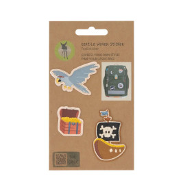 Vier gewebte Sticker - Vogel, Schatztruhe, Piratenflagge und Banane - auf brauner Kartonunterlage.