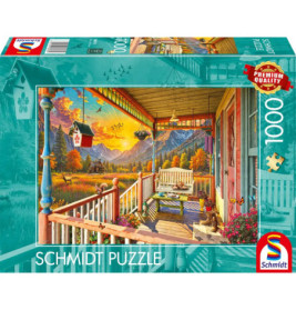 Eine bunte Puzzlebox zeigt eine Veranda mit Bank, Blumen, Bergen und einem Vogelhaus im Vordergrund.