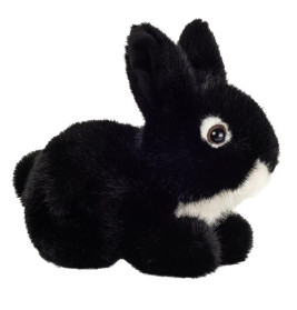 Ein schwarz-weißes Plüschkaninchen sitzt auf weißem Hintergrund und blickt nach rechts.