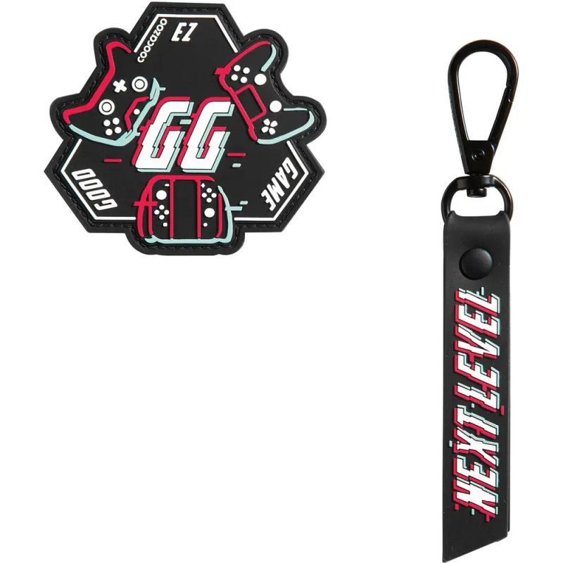 Sechseckiges GG-Badge mit Controllern und schwarzem NEXT LEVEL-Schlüsselanhänger mit roter und weißer Schrift.