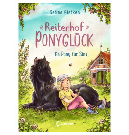 Ein Mädchen sitzt neben einem schwarzen Pony auf einer Wiese, im Hintergrund sind eine Scheune und Bäume zu sehen.