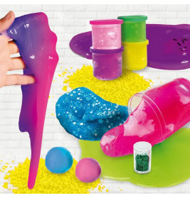 Buntes Slime, Glitzer und Pulver liegen mit kleinen Behältern und Kugeln auf weißem Ziegelhintergrund verteilt.