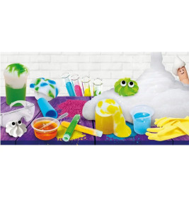 Bunte Laborausstattung mit Reagenzgläsern, Handschuhen, Schutzbrille, Schaum und Schleimfiguren auf einem lila Tisch.