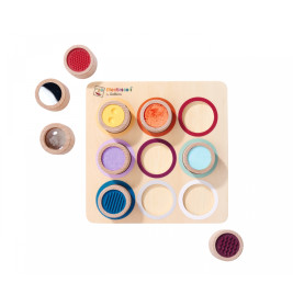 Montessori-Sinnesbrett mit neun strukturierten Holz-Zylindern und passenden farbigen Ringen auf quadratischer Basis.