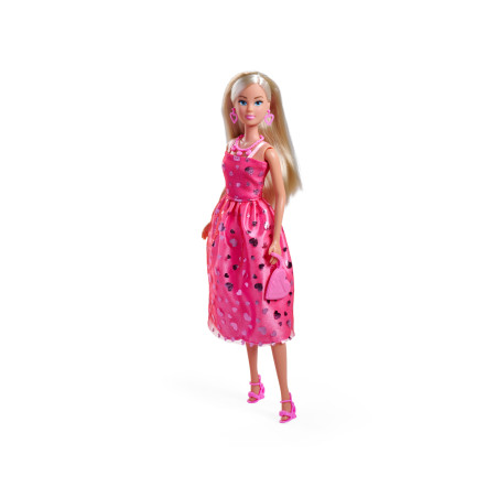 Eine blonde Puppe im rosa Kleid mit Herzchen, rosa Schuhen und passender Tasche steht vor weißem Hintergrund.