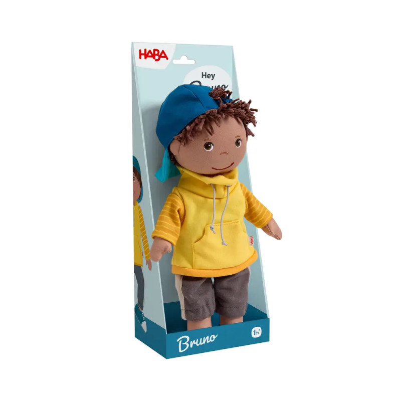 Plüschpuppe Bruno mit gelbem Hoodie und blauer Kappe in einer HABA-Box.