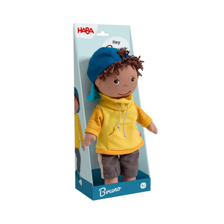 Plüschpuppe Bruno mit gelbem Hoodie und blauer Kappe in einer HABA-Box.