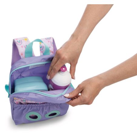 Eine Person legt Trinkflasche und Brotdose in einen lila Kinderrucksack mit türkisfarbenen Details.