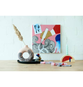 Kunstmaterialien und eine Vase stehen vor einem bunten Gemälde mit der Aufschrift "DO IT" an der Wand.