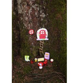 Kleine Feentür mit Leiter, Möbeln und Dekoration am Fuß eines moosbedeckten Baumstamms.