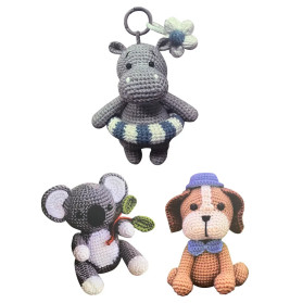 Drei gehäkelte Stofftiere: ein Nilpferd mit Schwimmring, ein Koala mit Blättern und ein Hund mit blauem Hut.