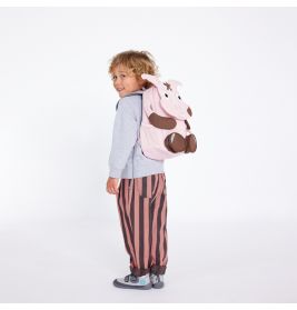 Ein Kind mit grauem Hoodie, gestreifter Hose und pinkem Tier-Rucksack lächelt in die Kamera.